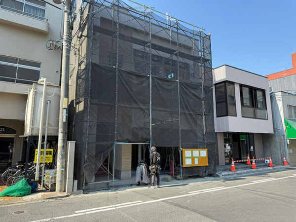 隣のビルと隣接した状態で、解体前の足場が組まれたビル